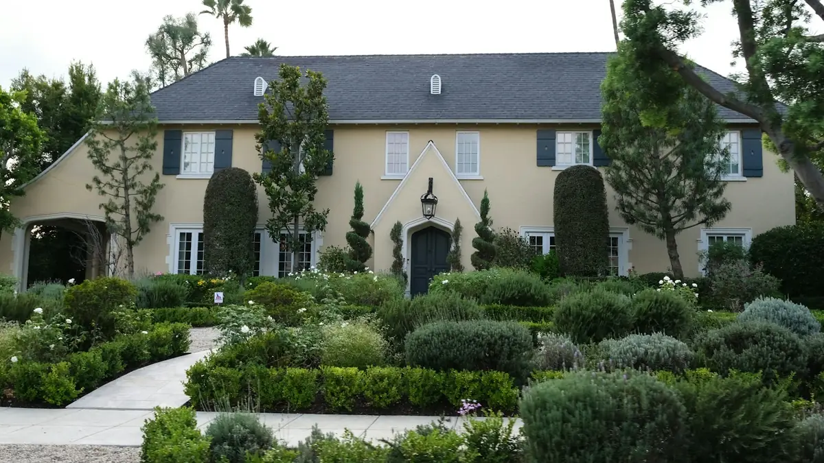 Two-story Mediterranean house behind clipped hedges - Water Heater Replacement in Whittier