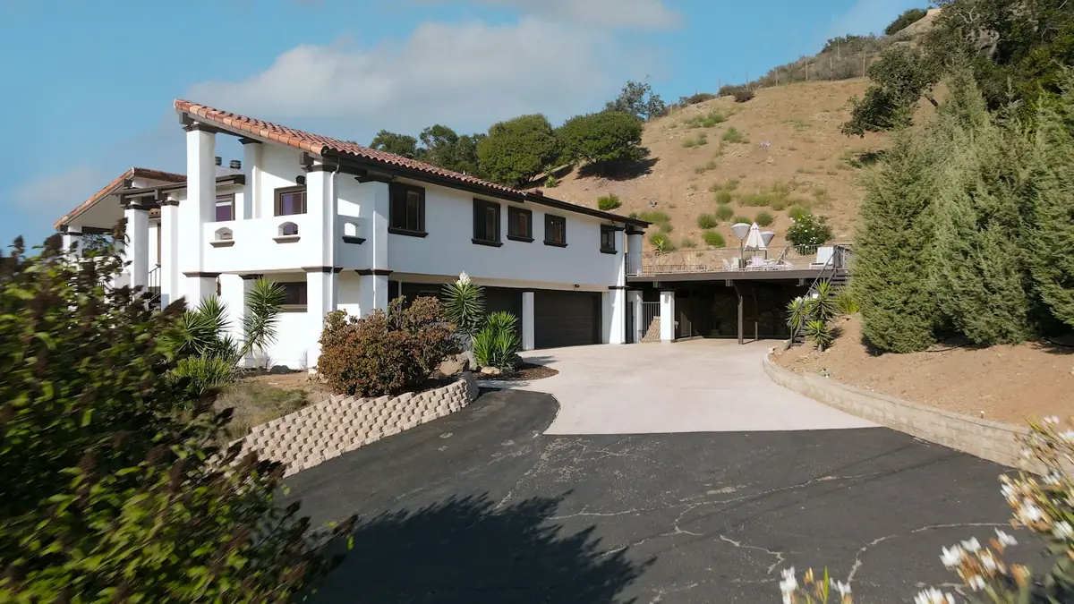 White Spanish-style house at the top of a hillside driveway
