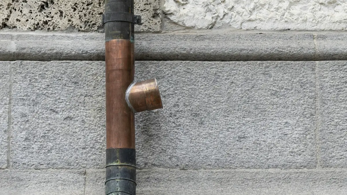 A copper pipe and fitting against a stone wall